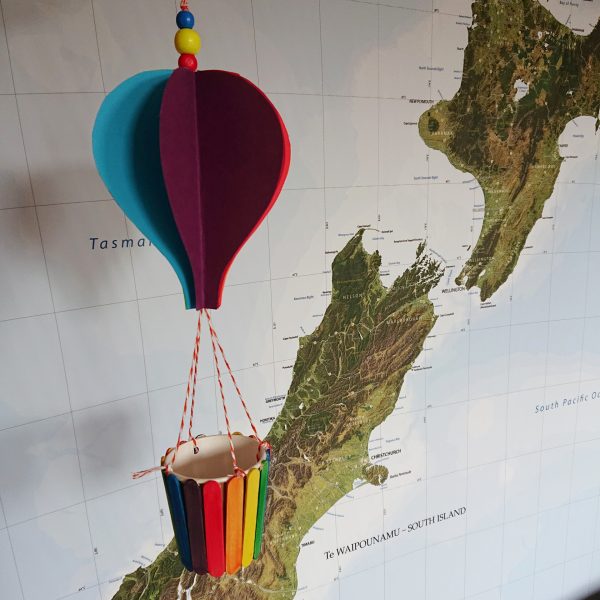 hot air balooon craft in front of new zealand map