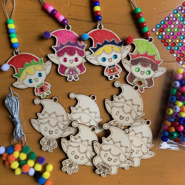 Wooden elf decorations with pony beads strung on top, surrounded by craft supplies